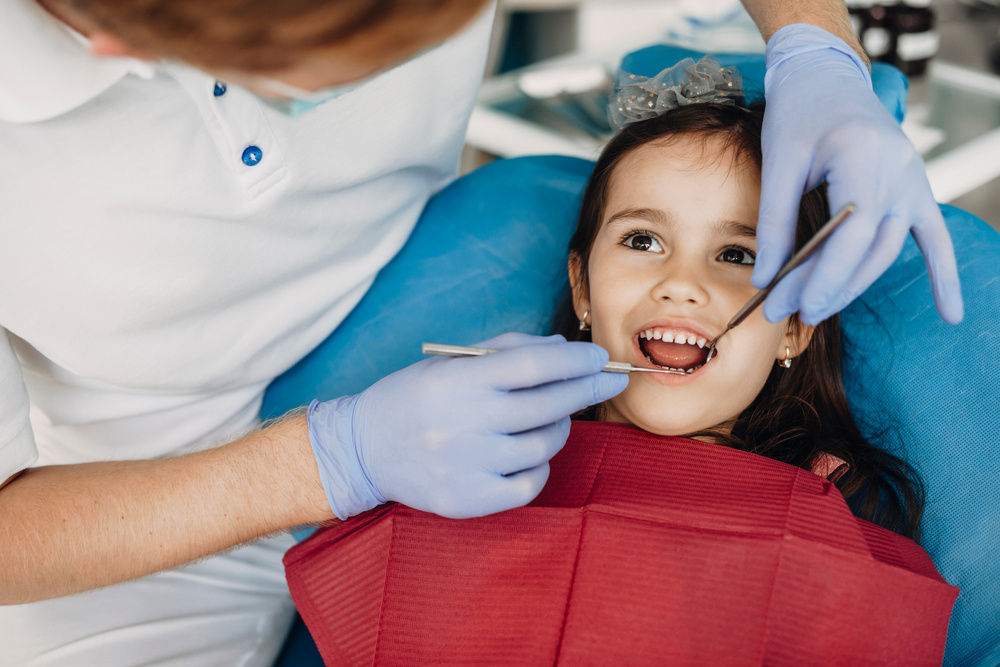 Close up of a cute little kid doing teeth surgery by a pediatric dentist.